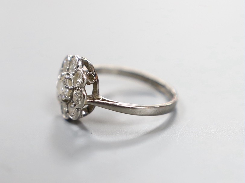 An 18ct, plat and nine stone diamond set flower head cluster ring, size L, gross weight 2.4 grams.
